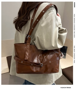 Detail of dark brown PU leather tote bag with metallic eyelet straps and vintage style