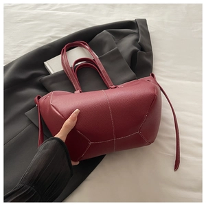 Detail of burgundy bucket bag featuring white contrast stitching and lychee grain leather