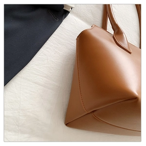 Close-up of the fine stitching and smooth brown leather texture on a tote bag corner
