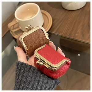 Close-up of mini leather coin purses in brown and red with gold metal clasps held by hand