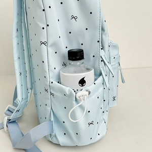 Blue polka dot backpack with bow pattern featuring a drawstring side pocket for water bottles