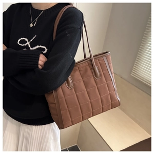 Brown quilted nylon tote bag with leather straps worn by model for casual daily use
