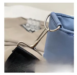 Detail shot of silver metal hook and black woven shoulder strap on blue nylon lunch bag