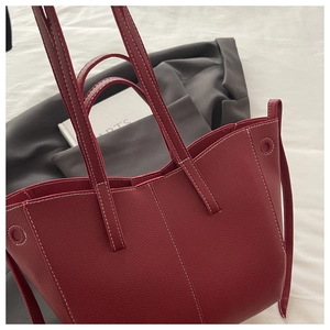 Detail of dark red lychee grain leather tote bag with white contrast stitching accents