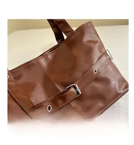 Detailed macro view of the brown leather tote bag with silver buckle and decorative strap