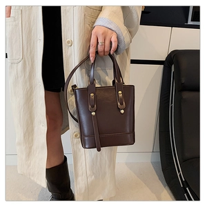Detail of deep brown retro leather tote bag featuring bronze metallic studs and buckles