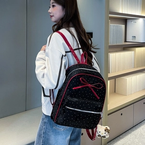 Polka dot backpack detail showing red patent leather bow and cute character charm