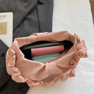 Chic pink pleated cloud shoulder bag showing interior storage capacity with everyday items