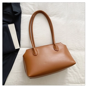 Macro shot of minimalist caramel brown tote bag showing smooth PU leather texture