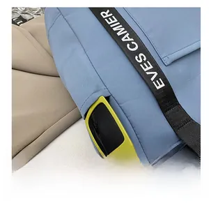 Detail of the side pocket on a blue waterproof tote bag with black lettered straps