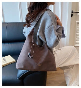 Dettaglio di una grande borsa hobo marrone con spalline larghe e scritte dorate eleganti