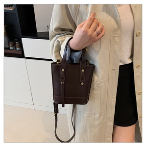 Detail of dark brown PU bucket bag with gold rivets and adjustable shoulder strap