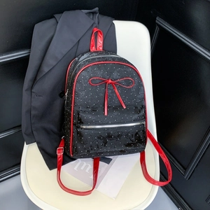 Close-up of black polka dot backpack with a red bow on a white chair in a studio