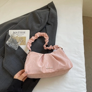 Pink pleated cloud bag with metallic logo on white fabric and grey blazer background