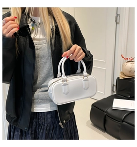 Close-up of a white jelly pillow bag with gold hardware held by a model in a modern setting