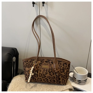 Detail of leopard print tote bag with golden FASHION tag and beaded tassel on soft rug