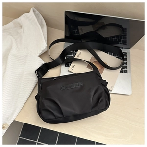 Macro shot of waterproof black nylon crossbody bag on a modern minimalist desk