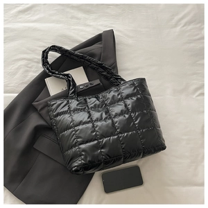 Close-up of black quilted puffer tote bag with glossy nylon texture and wide handles