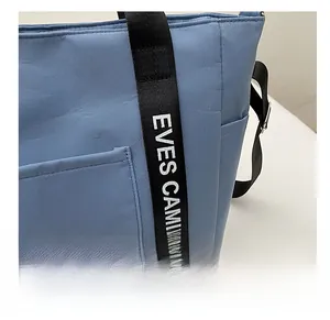 Detail of blue oxford tote bag with letter print straps and side storage pocket