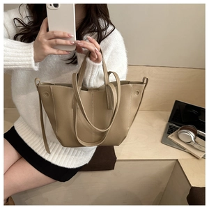 Detail of khaki pebbled leather tote bag with contrast stitching and dual carry straps