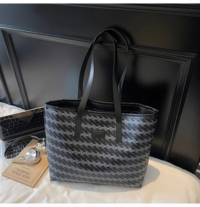 Close-up of high-capacity tote bag with gray wave pattern and black leather handles