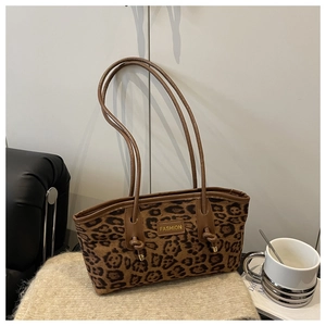 Detailed macro view of leopard print velvet texture and gold fashion logo on tote bag
