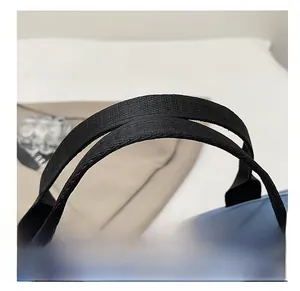 Detail shot of the reinforced black nylon handle and light blue canvas material