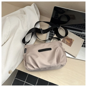 Minimalist beige nylon crossbody bag displayed with office laptop and stylish magazines