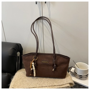 Detail of a large vintage brown faux suede tote bag with a wooden bead charm and fashion tag