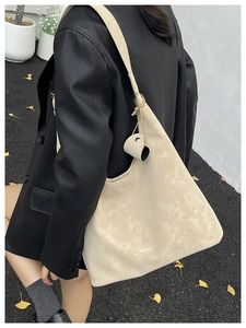 Detail shot of the large beige hobo bag on shoulder, showcasing pebbled texture and wide strap
