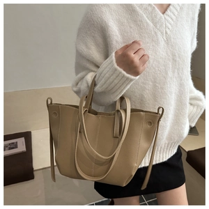 Detail of khaki pebbled leather tote bag showing double handles and stitching texture