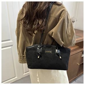 Detail of black suede tote bag featuring thin shoulder straps and golden FASHION logo