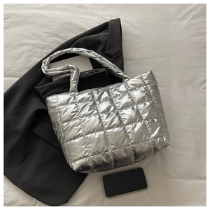 Close-up of the silver quilted puffer tote bag with metallic finish on black suit fabric