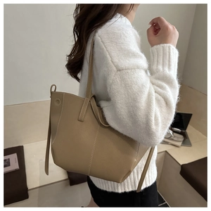 Close-up of khaki pebbled leather bucket bag with white contrast stitching detail