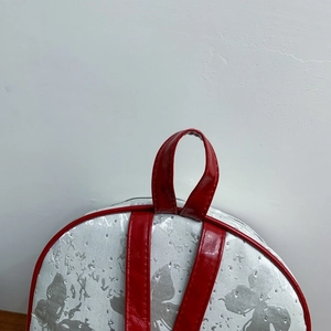 Detail of silver butterfly print backpack with red patent leather trim and metal rivets