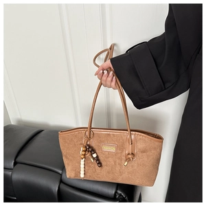 Detail of brown faux suede tote bag with long straps and beaded charm accessory