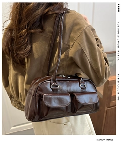 Detail of glossy brown patent leather shoulder bag with two front flap pockets
