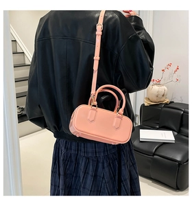 Model wearing a glossy pink mini Boston bag as a crossbody over a black leather jacket
