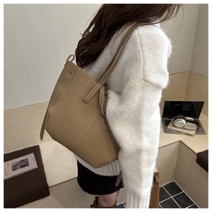 Detail of camel textured leather tote bag with white contrast stitching on shoulder strap