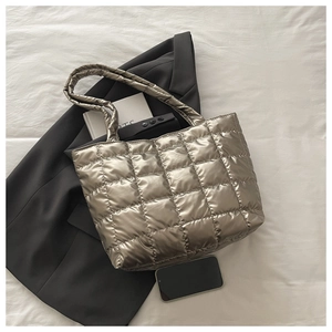 Flat lay of a silver quilted tote bag with padded shoulder straps on a grey blazer
