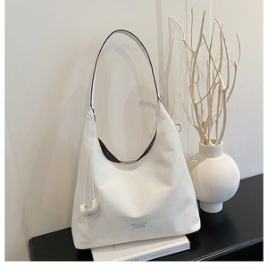 Dettaglio della borsa hobo in pelle bianca con logo del marchio e ciondolo rotondo