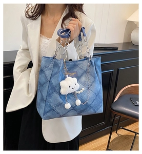 Close-up of quilted denim tote bag with silver chain strap and plush cloud pendant charm