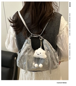 Detail of silver metallic pleated tote bag with a white plush cloud charm accessory