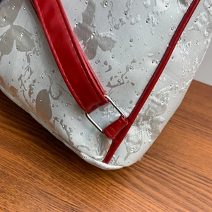 Detailed close-up of a white backpack with silver butterfly prints and red straps