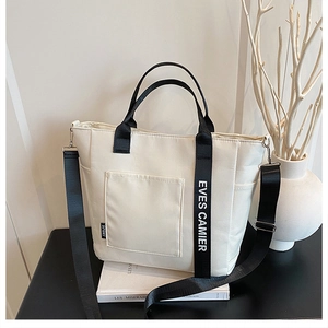 Detail of minimalist cream canvas lunch bag with black straps and sport label detail