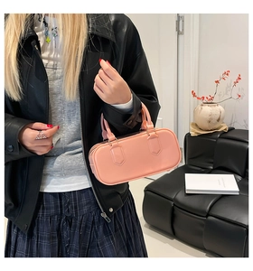 Close-up of pink jelly PVC boston bag with glossy finish held by a model in leather jacket