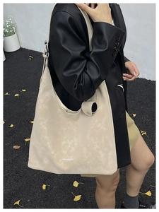 Detail of beige hobo bag in vintage matte leather with logo on ginkgo leaf street