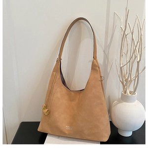 Dettaglio del logo argentato e della texture scamosciata su una borsa a spalla hobo cammello