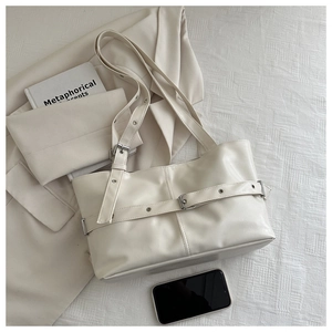 Detail view of cream leather tote bag with metal buckle strap and textured finish