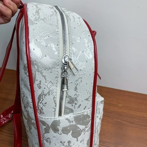 Close-up of silver butterfly jacquard fabric with red leather trim and metal zippers